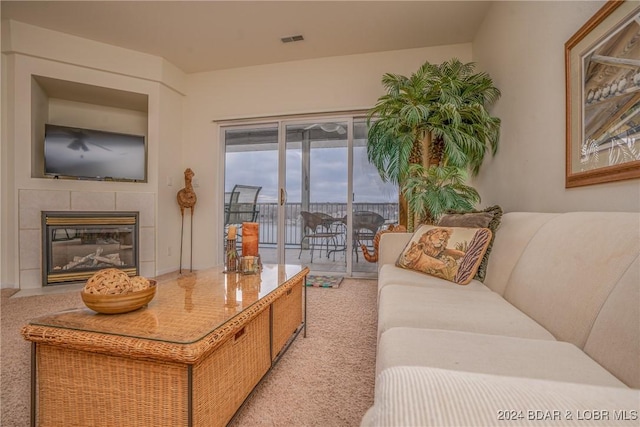 living room featuring light colored carpet and a tiled fireplace