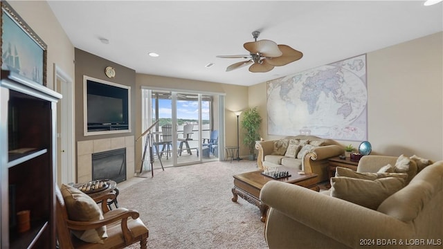 carpeted living room featuring a fireplace and ceiling fan