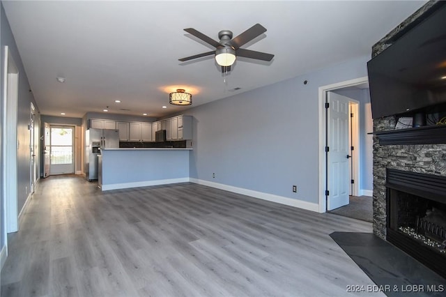 unfurnished living room featuring ceiling fan, a fireplace, and wood-type flooring