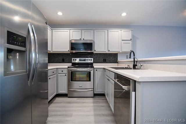 kitchen featuring sink, white cabinetry, light hardwood / wood-style flooring, appliances with stainless steel finishes, and decorative backsplash