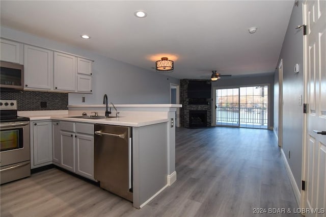 kitchen with sink, a fireplace, kitchen peninsula, and appliances with stainless steel finishes