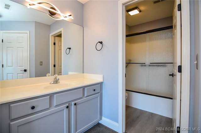 bathroom with hardwood / wood-style flooring, vanity, toilet, and an enclosed shower