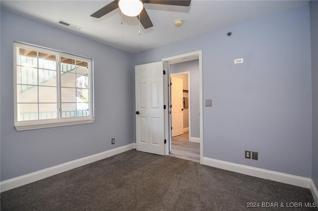 empty room featuring dark carpet and ceiling fan