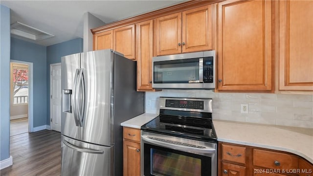 kitchen with backsplash, light stone countertops, dark wood-type flooring, and appliances with stainless steel finishes