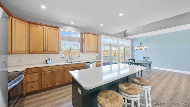 kitchen featuring stainless steel appliances, a kitchen island, light hardwood / wood-style floors, and sink