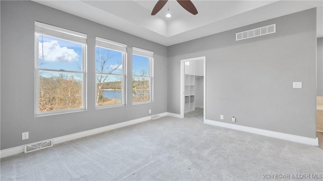 unfurnished bedroom featuring ceiling fan, light colored carpet, a walk in closet, and a closet