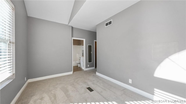 unfurnished room with light colored carpet and vaulted ceiling