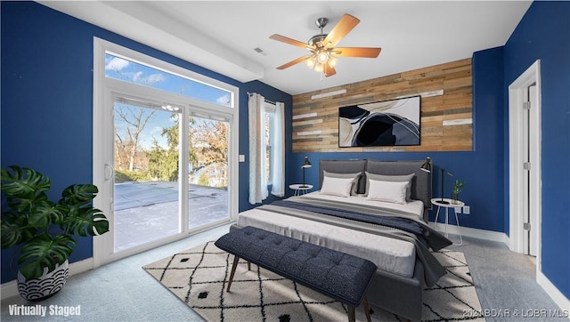 carpeted bedroom with access to outside, ceiling fan, and wood walls