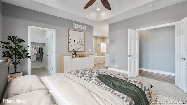 bedroom featuring ensuite bath, a spacious closet, ceiling fan, light hardwood / wood-style flooring, and a closet