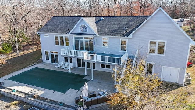 back of property featuring a balcony, central AC, a covered pool, and a patio area