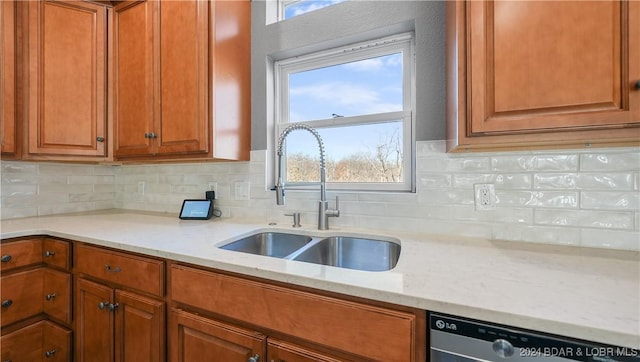 kitchen featuring dishwashing machine, light stone countertops, sink, and tasteful backsplash