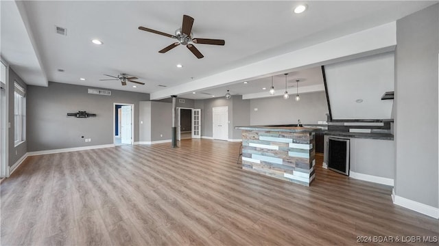 unfurnished living room featuring ceiling fan, light hardwood / wood-style floors, and wine cooler