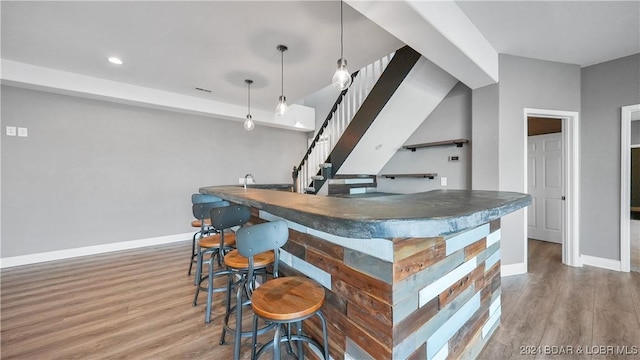 bar featuring decorative light fixtures and hardwood / wood-style flooring