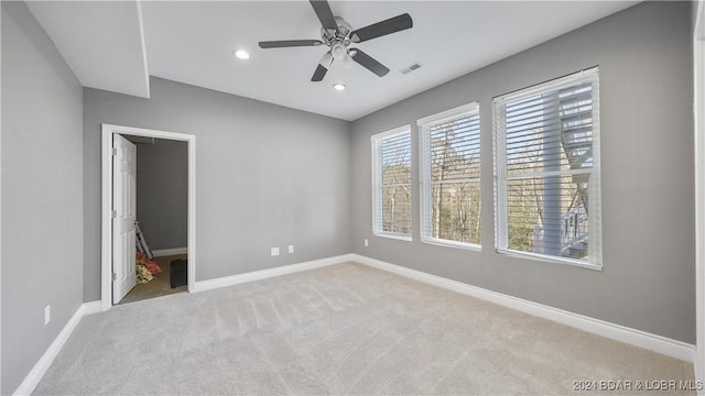 unfurnished bedroom featuring a closet, a walk in closet, light colored carpet, and ceiling fan