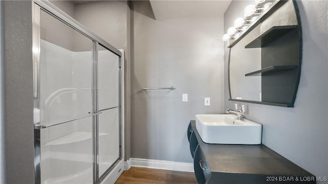 bathroom featuring wood-type flooring, a shower with shower door, and sink