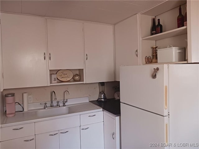 kitchen with white cabinetry, sink, and white fridge