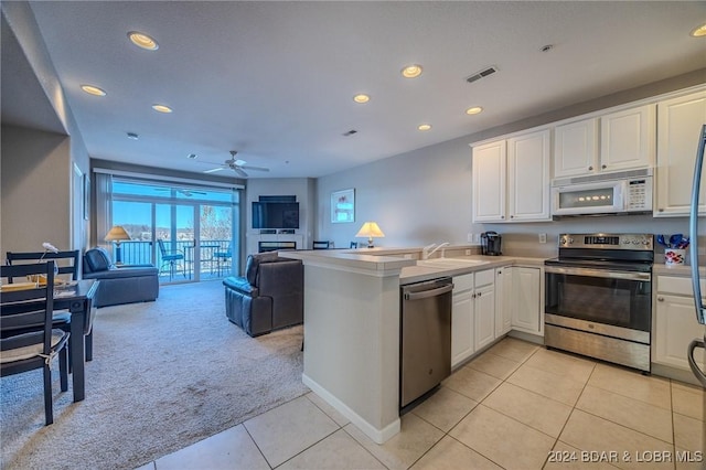 5450 Christopher Ln Unit 415, Osage Beach, MO 65065 - kitchen with appliances with stainless steel finishes, light carpet, light tile patterned flooring, recessed lighting, and white cabinetry