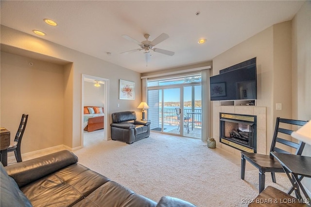 carpeted living room featuring ceiling fan and a tile fireplace