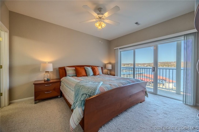 carpeted bedroom featuring access to exterior, ceiling fan, and a water view