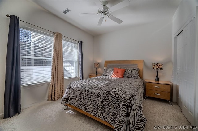 bedroom featuring light colored carpet, ceiling fan, and a closet