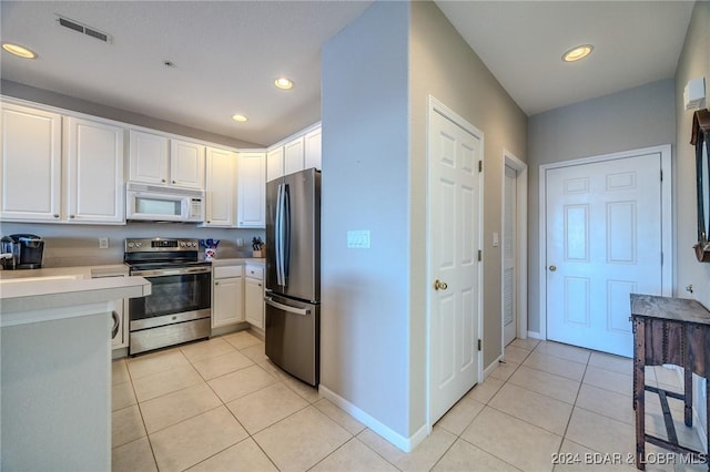 kitchen with light tile patterned floors, stainless steel appliances, and white cabinets