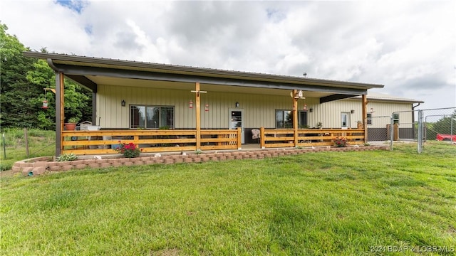 rear view of house featuring covered porch and a lawn