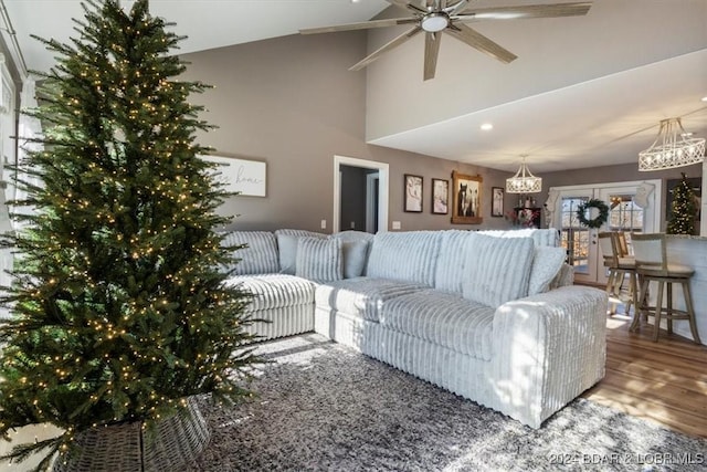 living room featuring hardwood / wood-style floors, ceiling fan with notable chandelier, and vaulted ceiling