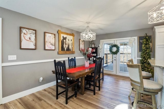 dining room featuring light wood-type flooring, french doors, and an inviting chandelier