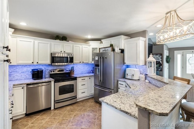 kitchen with pendant lighting, white cabinets, a kitchen breakfast bar, appliances with stainless steel finishes, and kitchen peninsula