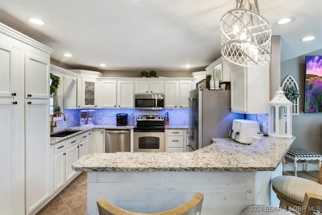 kitchen with backsplash, a breakfast bar, stainless steel appliances, sink, and decorative light fixtures