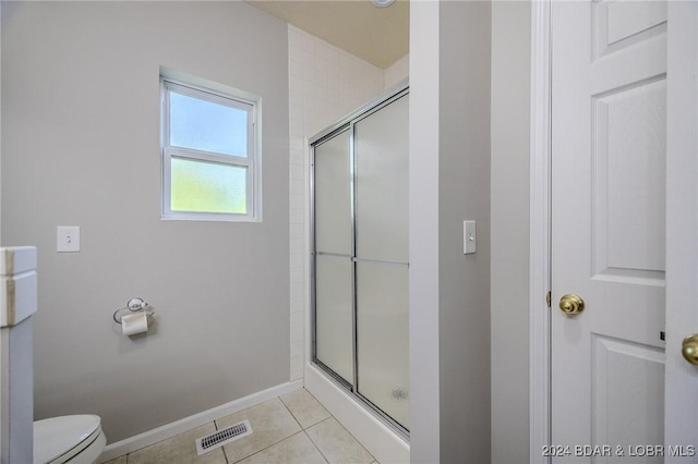 bathroom featuring tile patterned flooring, toilet, and a shower with door