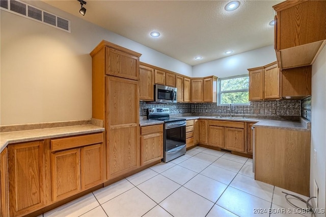 kitchen with decorative backsplash, light tile patterned flooring, sink, and appliances with stainless steel finishes