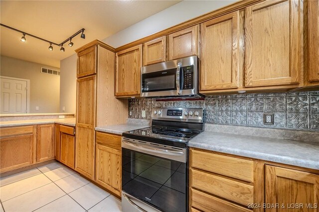 kitchen featuring backsplash, light tile patterned floors, and appliances with stainless steel finishes