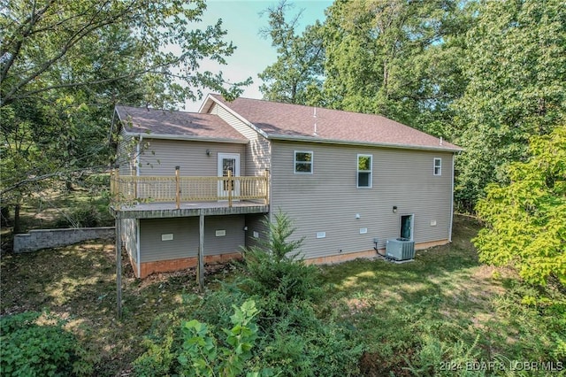 rear view of house with central AC unit and a lawn