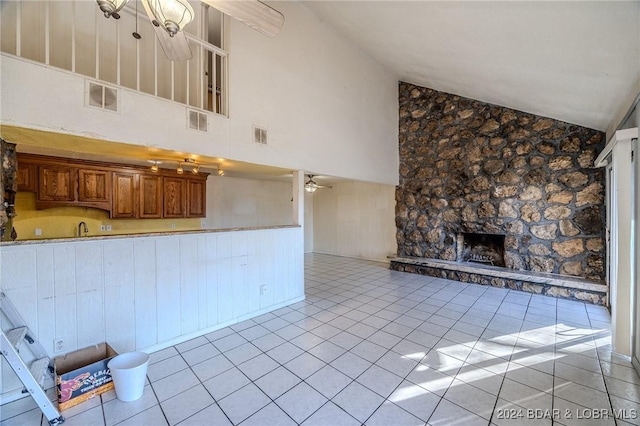 unfurnished living room with a fireplace, light tile patterned floors, high vaulted ceiling, and ceiling fan