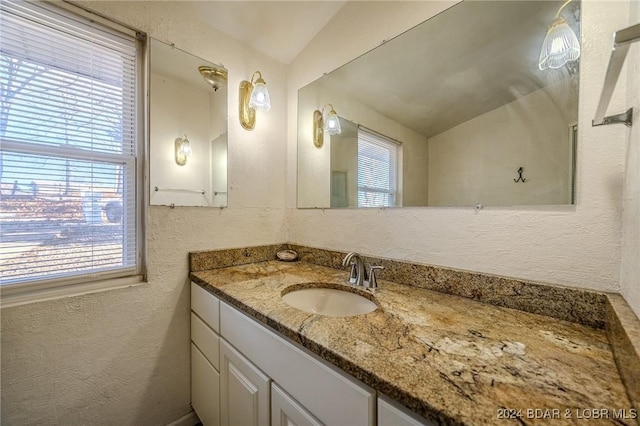 bathroom with plenty of natural light, vanity, and lofted ceiling