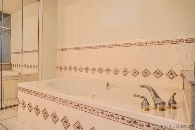 bathroom with tile patterned flooring, a relaxing tiled tub, and tile walls