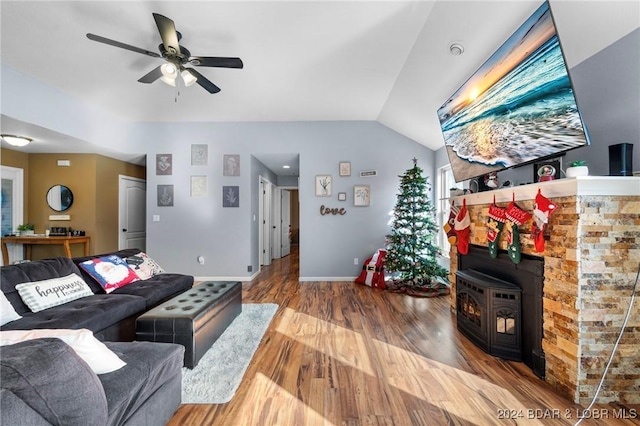 living room with lofted ceiling, ceiling fan, wood-type flooring, and a wood stove