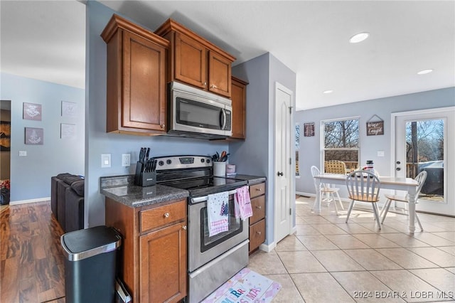 kitchen with light tile patterned flooring, dark stone countertops, and stainless steel appliances