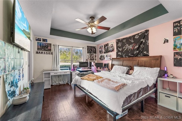 bedroom featuring a raised ceiling, ceiling fan, and dark wood-type flooring