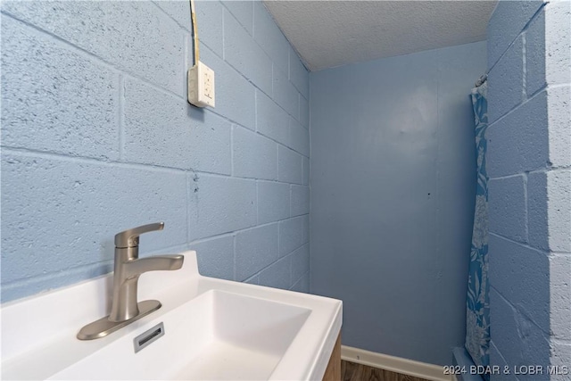 bathroom with a textured ceiling, hardwood / wood-style flooring, and sink