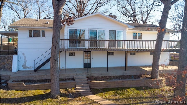 rear view of property featuring a wooden deck and a patio area