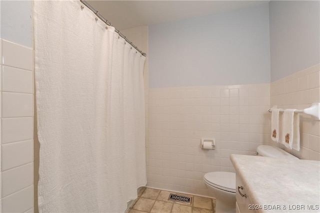 bathroom featuring vanity, tile walls, and toilet