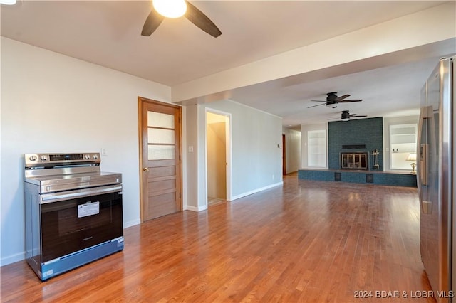 unfurnished living room with ceiling fan, wood-type flooring, and a brick fireplace