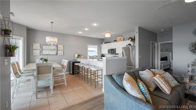 kitchen with a breakfast bar, stainless steel appliances, pendant lighting, light hardwood / wood-style flooring, and white cabinets