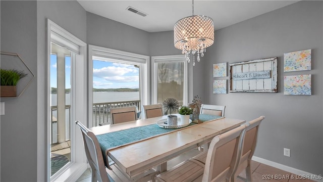 dining room featuring a water view, light tile patterned floors, and a notable chandelier