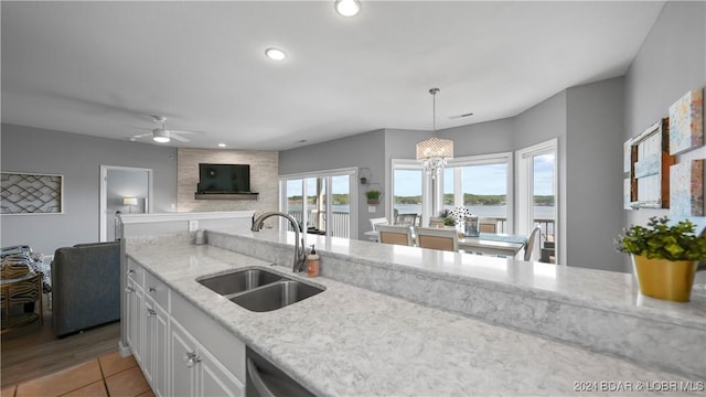 kitchen featuring light stone countertops, sink, light hardwood / wood-style flooring, white cabinets, and hanging light fixtures