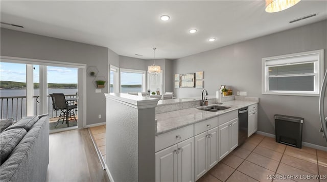 kitchen with kitchen peninsula, white cabinets, sink, and a water view