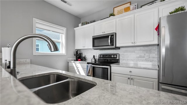 kitchen featuring white cabinets, light stone counters, sink, and appliances with stainless steel finishes