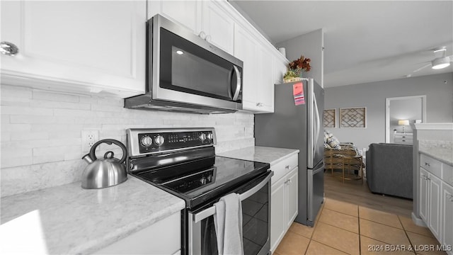 kitchen featuring ceiling fan, decorative backsplash, light tile patterned floors, appliances with stainless steel finishes, and white cabinetry